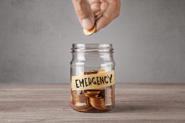 Emergency. Glass jar with coins and an inscription Emergency. Man holds  coin in his hand