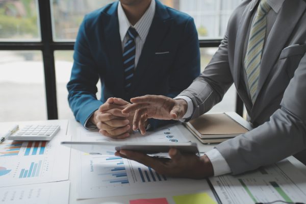 Financial analysts analyze business financial reports on a digital tablet planning investment project during a discussion at a meeting of corporate showing the results of their successful teamwork.